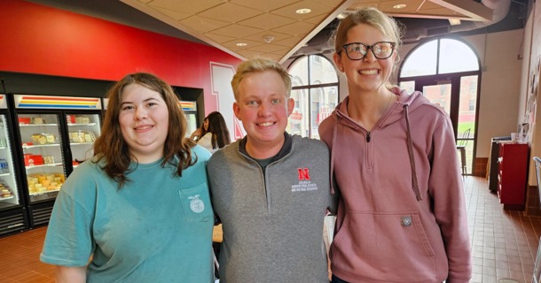 Carie Goodwater (left) and Melany Preister (right), students at Boone Central High School, pose with Brian Mock (center), a Husker student mentor who graduated in May.